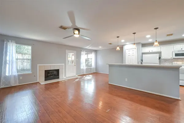 an empty room with wooden floor fireplace and windows