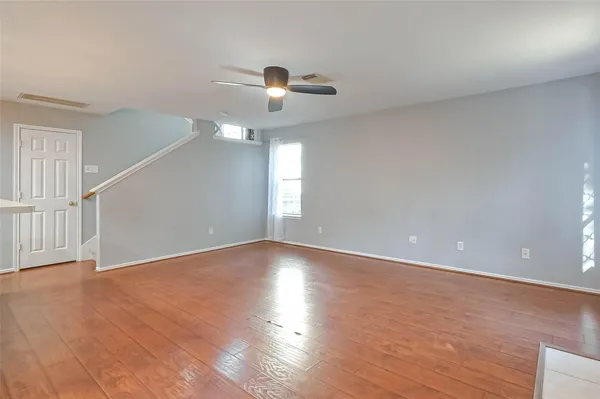 a view of an empty room with wooden floor and a window