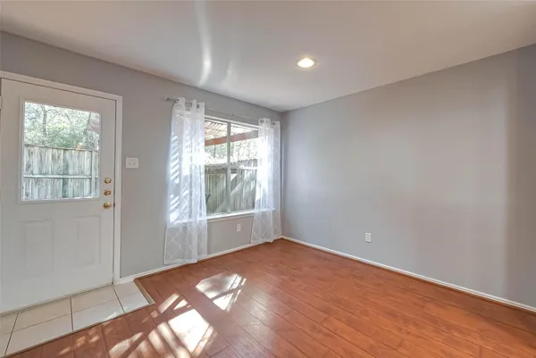 an empty room with wooden floor and windows