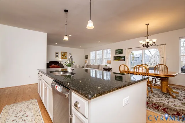 a kitchen with stainless steel appliances granite countertop a sink a stove top oven a counter space and living room view