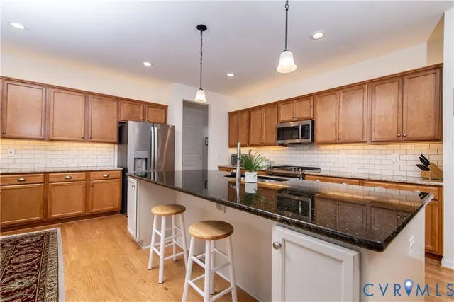 a kitchen with stainless steel appliances granite countertop a sink a stove a refrigerator cabinets and chairs