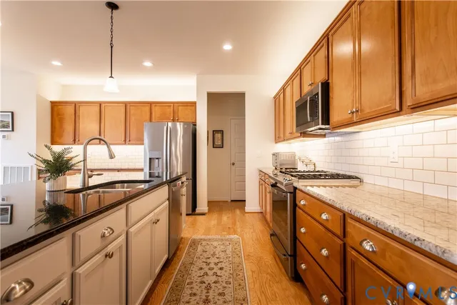a kitchen with stainless steel appliances granite countertop a stove a sink and a refrigerator