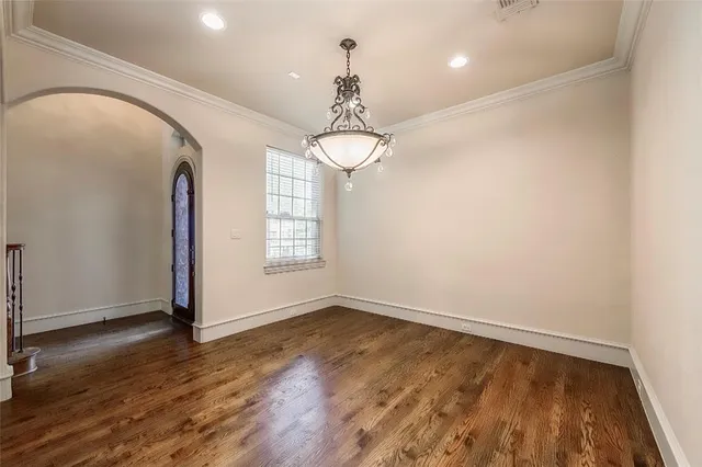 an empty room with wooden floor chandelier and windows