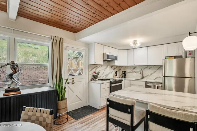 a kitchen with stainless steel appliances granite countertop a refrigerator a sink dishwasher a stove and white countertops with wooden floor