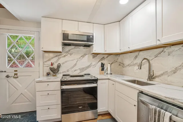a kitchen with white cabinets and appliances