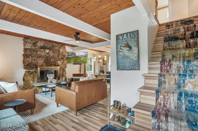 a living room with couches a fireplace and kitchen view with wooden floor