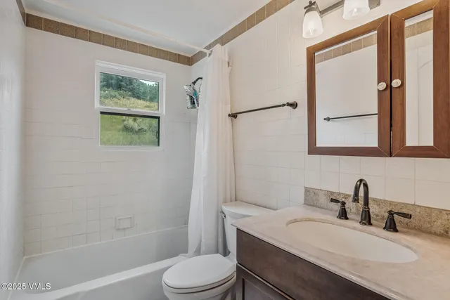 a bathroom with a granite countertop sink toilet a mirror and shower