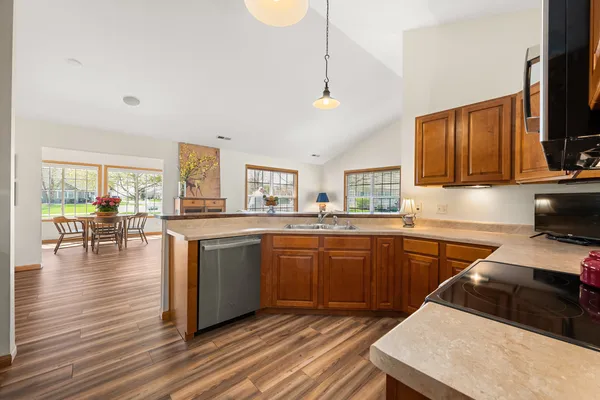 a kitchen with stainless steel appliances granite countertop a stove a sink dishwasher a microwave oven with cabinets and wooden floor