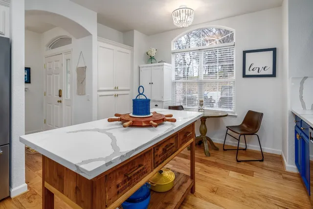 a living room with stainless steel appliances furniture a chandelier and a table