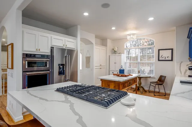a kitchen with stainless steel appliances a table a stove a refrigerator and cabinets