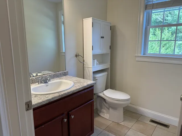 a bathroom with a granite countertop toilet a sink and a window