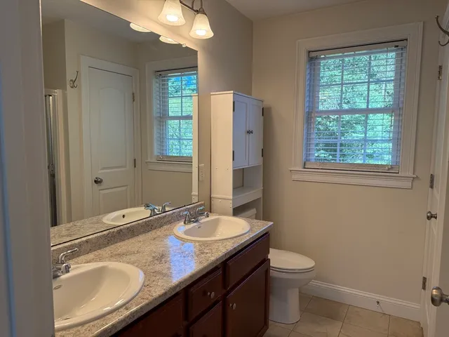 a bathroom with a granite countertop toilet sink and mirror