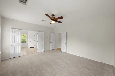 an empty room with closet and a chandelier fan