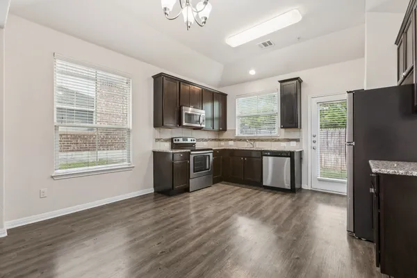 a kitchen with stainless steel appliances granite countertop a stove a sink dishwasher a refrigerator and a microwave oven with wooden floor