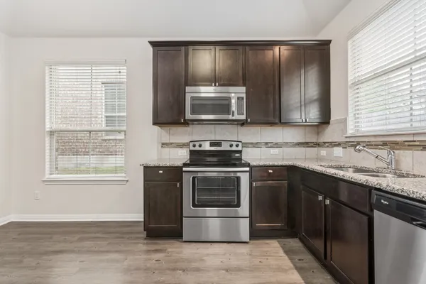 a kitchen with granite countertop a stove top oven sink and cabinets