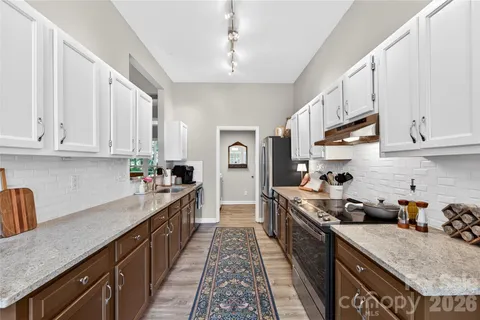 a kitchen with stainless steel appliances granite countertop a stove a sink dishwasher and cabinets with wooden floor