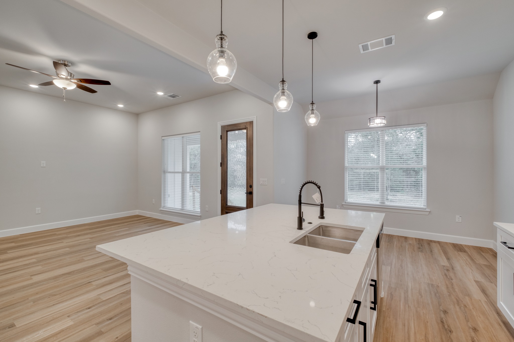 116 Pine Point Cove Elgin, TX 78621 - Photo 12 of 27 Kitchen island featuring a white countertop and a double-basin sink with a matte black faucet