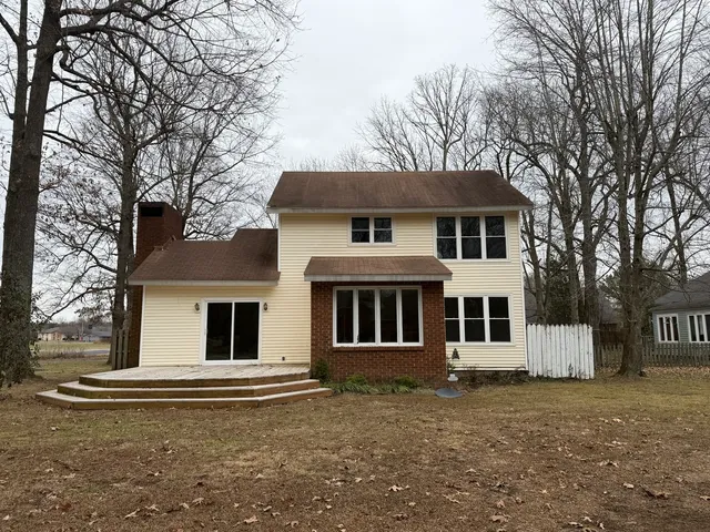 a view of a white house with a yard and large tree