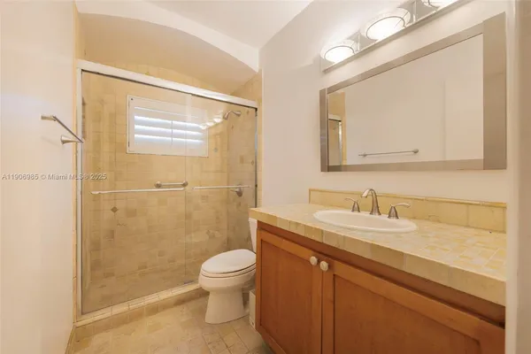 a bathroom with a granite countertop sink toilet a mirror and shower