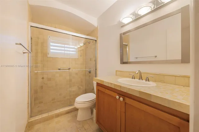a bathroom with a granite countertop sink toilet a mirror and shower