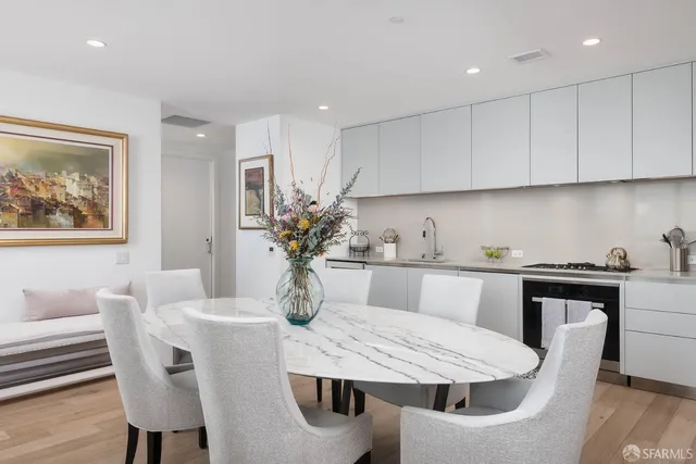 a kitchen with stainless steel appliances kitchen island granite countertop a dining table chairs and white cabinets