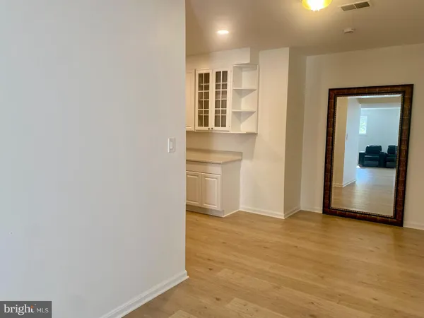 a view of an empty room with wooden floor and a bathroom