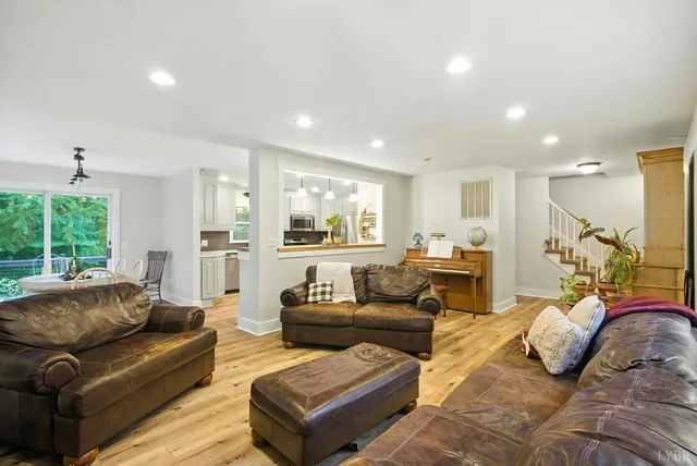a living room with furniture kitchen view and a large window