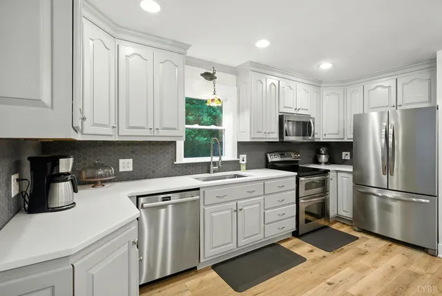 a kitchen with white cabinets stainless steel appliances and a window
