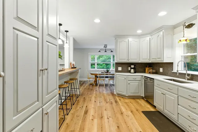 a kitchen with white cabinets and wooden floors