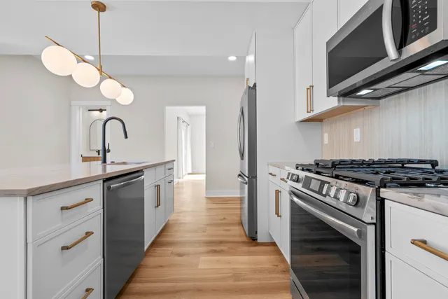 a kitchen with stainless steel appliances granite countertop a stove a sink and a microwave