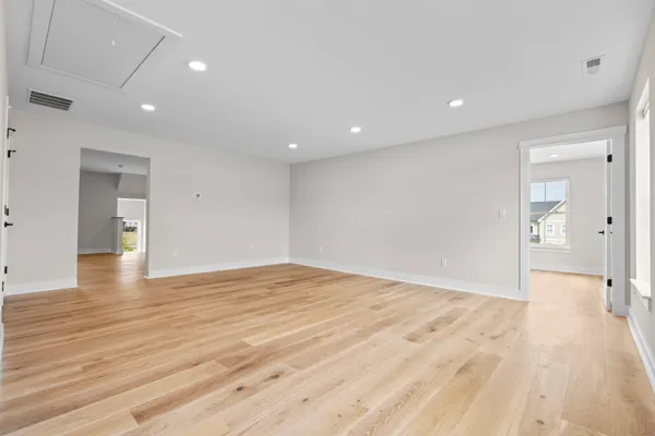 a view of an empty room with wooden floor and a bathroom