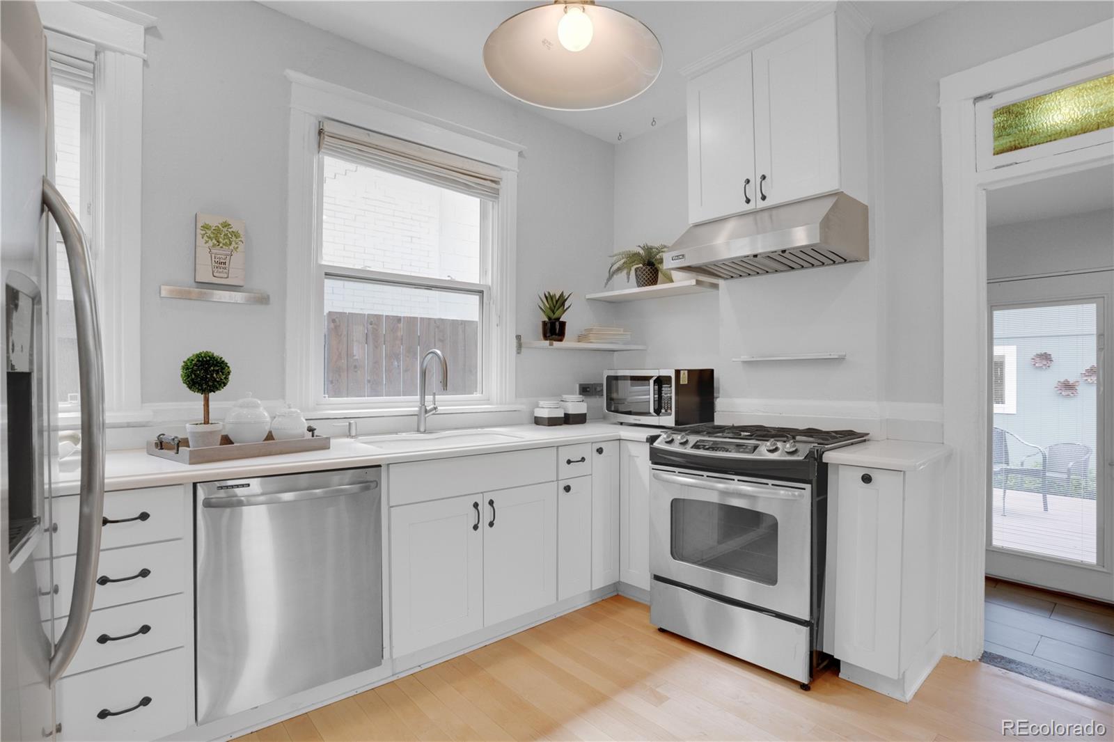 1283 Madison Street Denver, CO 80206 - Photo 12 of 34 a kitchen with stainless steel appliances granite countertop a sink and a stove next to a window