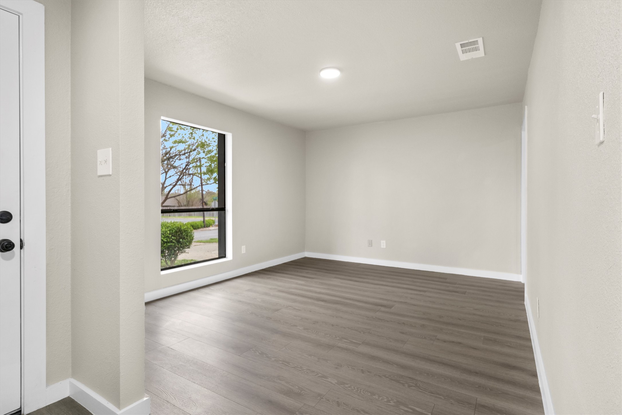 502 Pin Tail Lane Taylor, TX 76574 - Photo 8 of 26 Room featuring wood-finish flooring, a modern flush-mount ceiling light, and a large window with white trim