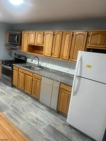 a kitchen with granite countertop cabinets stainless steel appliances a sink and a window