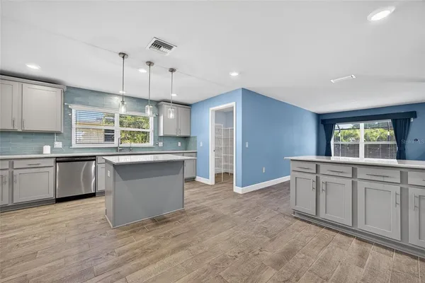a large kitchen with kitchen island a sink dishwasher a stove and white cabinets with wooden floor