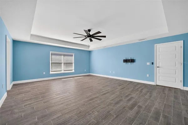 an empty room with wooden floor and ceiling fan