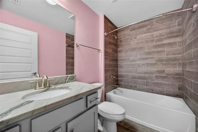 a bathroom with a granite countertop sink a toilet and bathtub
