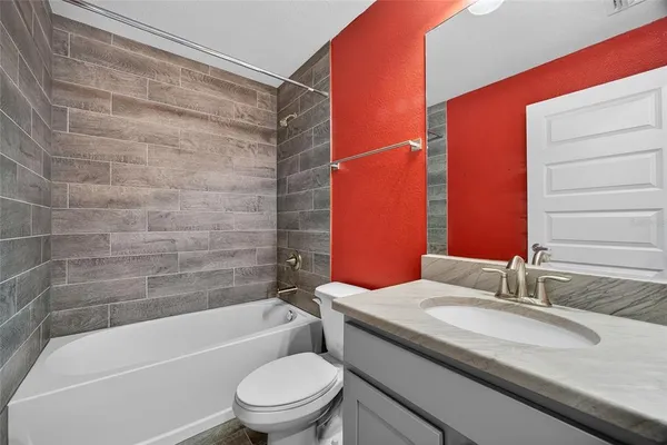 a bathroom with a granite countertop bathtub shower sink vanity and toilet