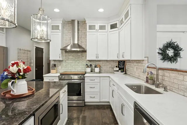 a kitchen with stainless steel appliances granite countertop a sink dishwasher stove and refrigerator with wooden floor