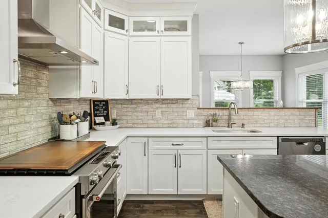 a kitchen with granite countertop a sink a stove and cabinets