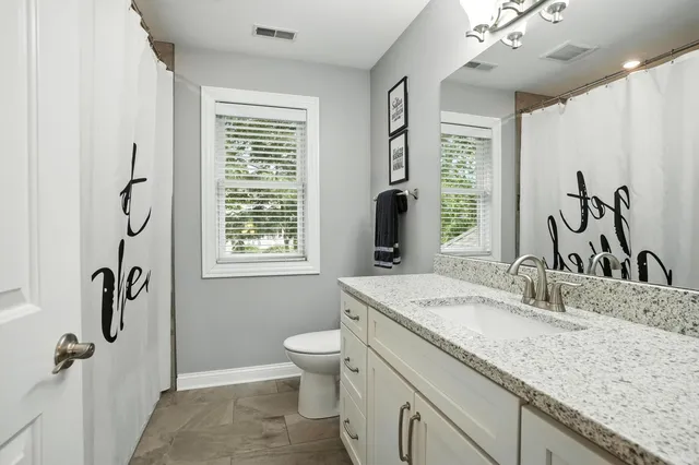 a bathroom with a granite countertop sink a large mirror and a bathtub