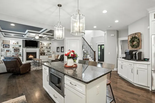 a kitchen with kitchen island granite countertop a stove a sink a oven and a fireplace with wooden floor
