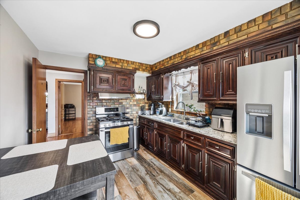6140 South Kostner Avenue Chicago, IL 60629 - Photo 7 of 24 a kitchen with stainless steel appliances granite countertop a stove top oven a refrigerator a sink and dishwasher with wooden floor