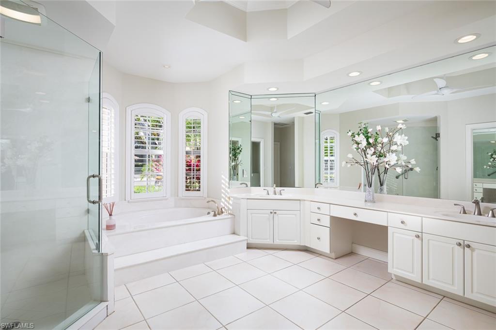 6900 Mill Run Road Naples, FL 34109 - Photo 22 of 31 a large white bathroom with a large mirror vanity a bathtub and a shower