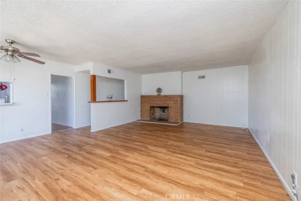 a view of empty room with wooden floor and fireplace