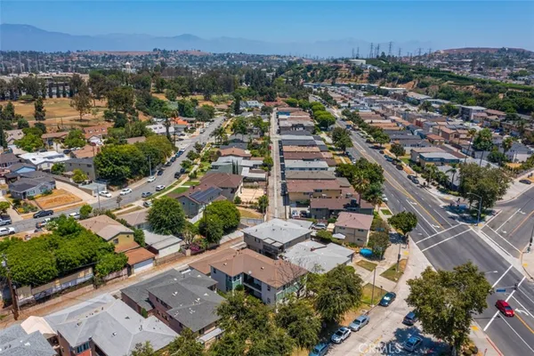 an aerial view of a city with lots of residential buildings ocean and mountain view in back