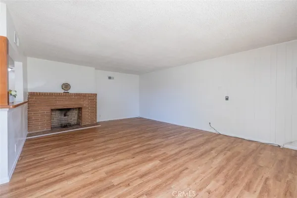 a view of empty room with wooden floor and fireplace