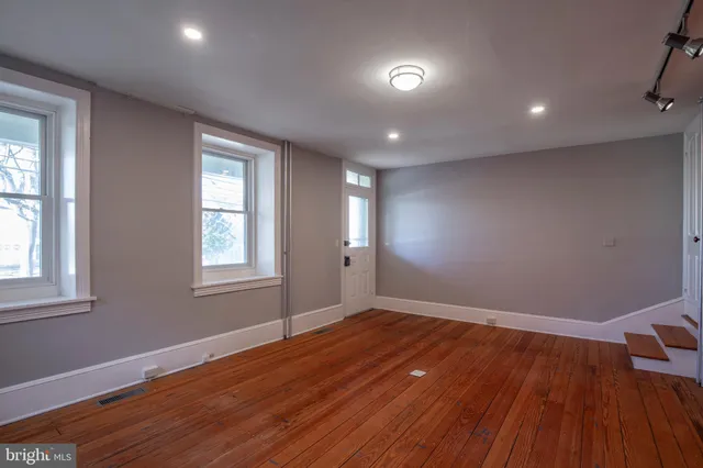 a view of an empty room with wooden floor and window