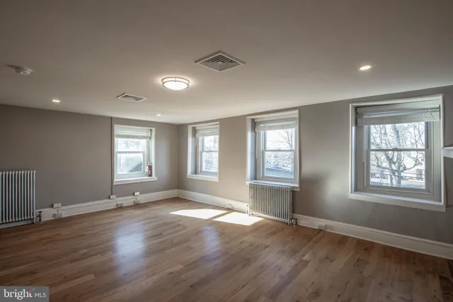 a view of empty room with wooden floor and window