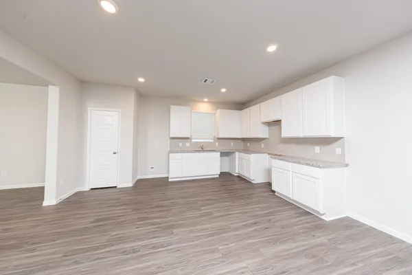 a large kitchen with a sink and dishwasher a stove top oven with wooden floor